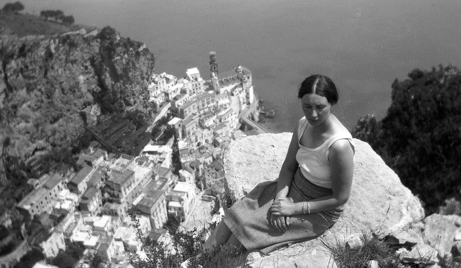 Escher photographs his wife Jetta with the Italian town Atrani, on the Amalfi coast, in the background.