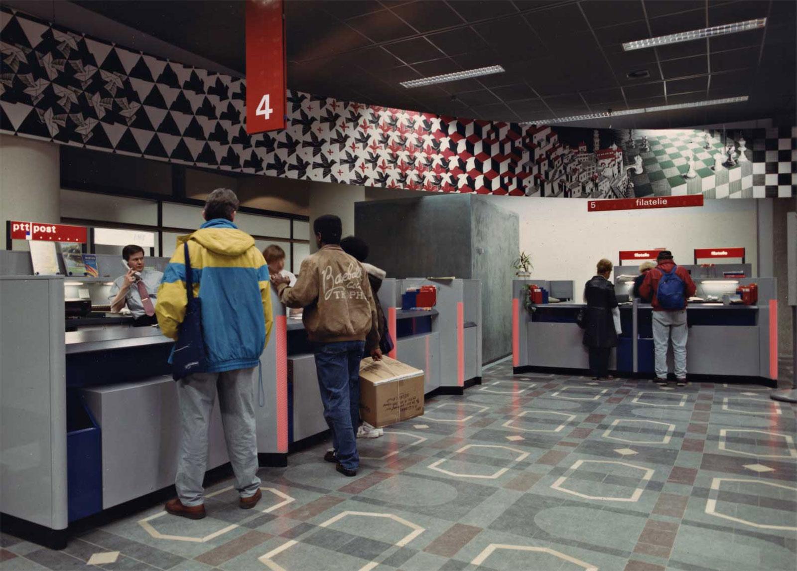 <p>De centrale publieksruimte met de loketten met bovenlangs Eschers metamorfose. Verzameling Beeld en Geluid Den Haag | Fotograaf onbekend | jaren 90</p>