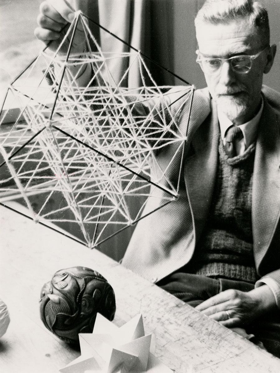 <p>M.C. Escher met een zelfgemaakt draadmodel van een kubus, jaartal onbekend</p>